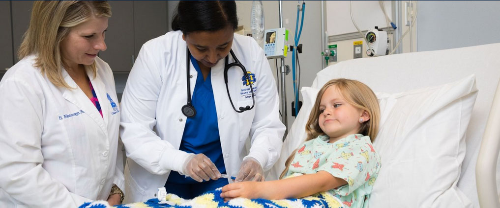 Professor standing next to student working with a patient.