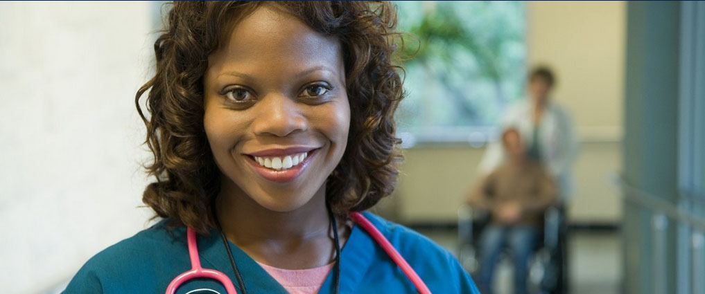 Nurse standing in a hallway smiling.