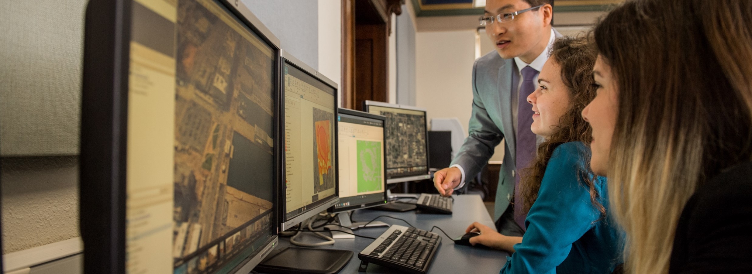 View of students and professor looking at a computer monitor.