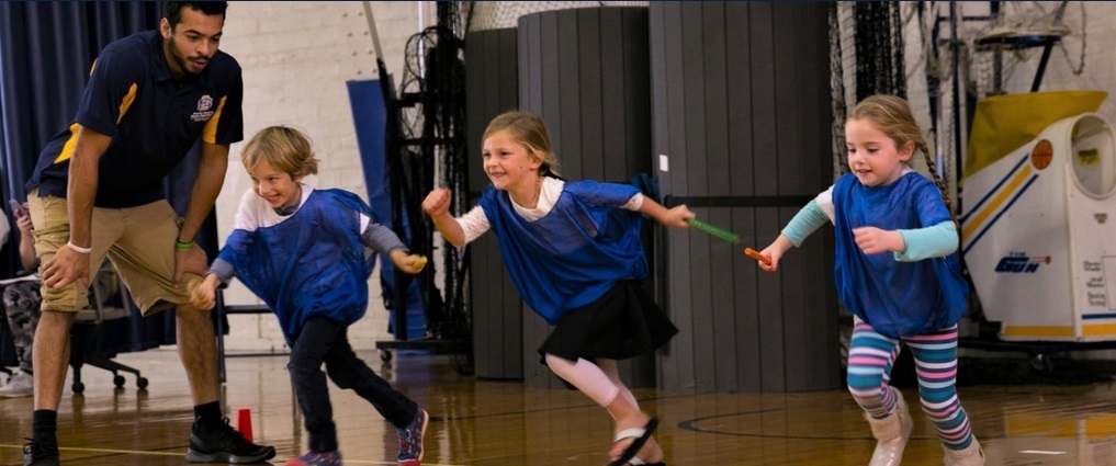 Student teacher working with young children that are running.