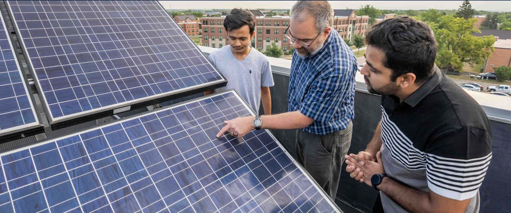 Two students and instructor looking at solar panels.