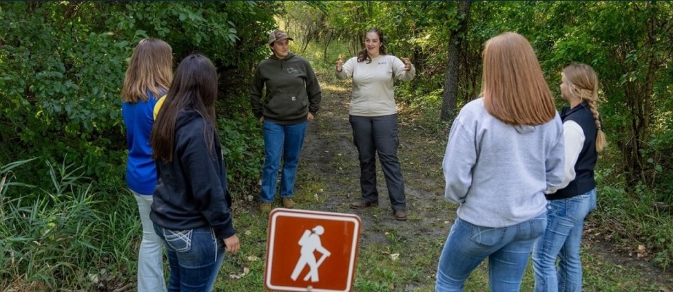 Students standing with an instructor on a walking trail.