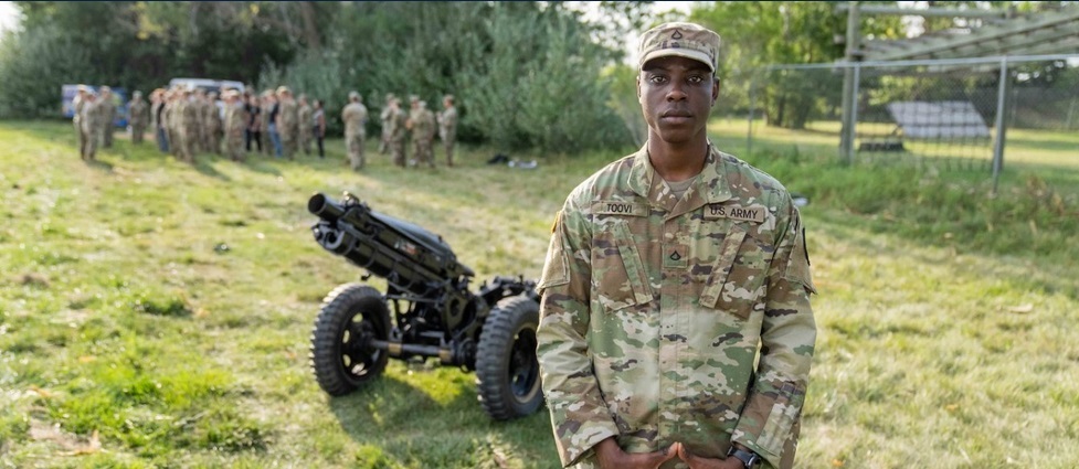 Cadet standing in front of a cannon.