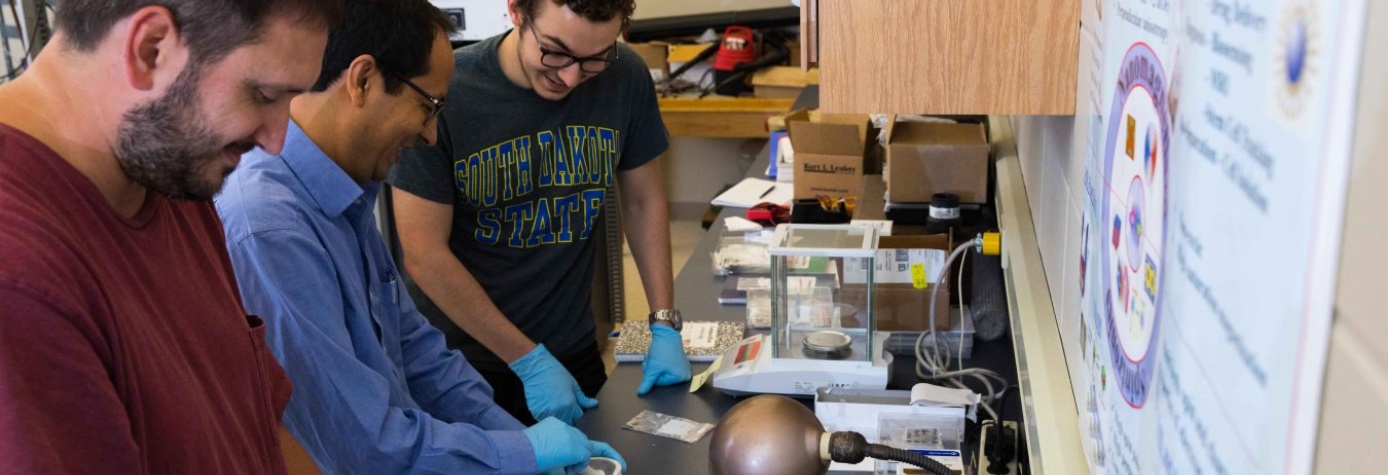 Physics students and professor in a lab.