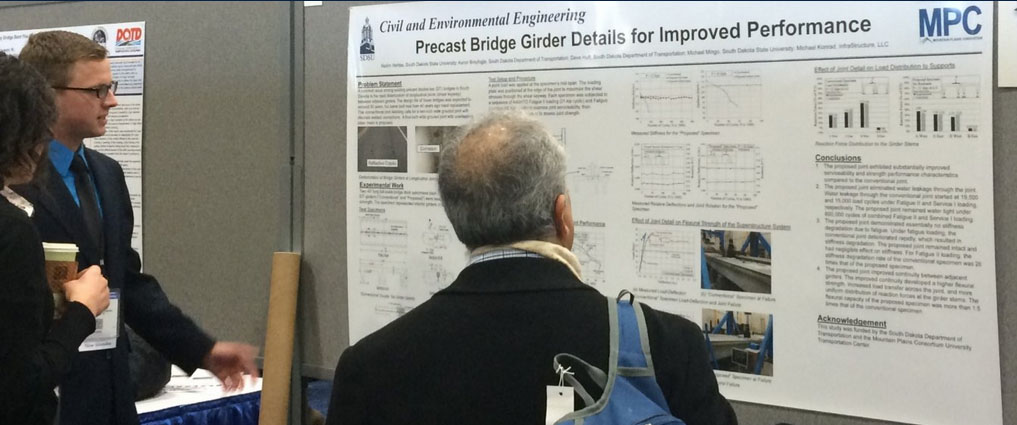 Researchers looking at a poster on precast bridge girder details for improved performance.