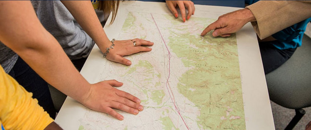 Students and professor looking at a map.