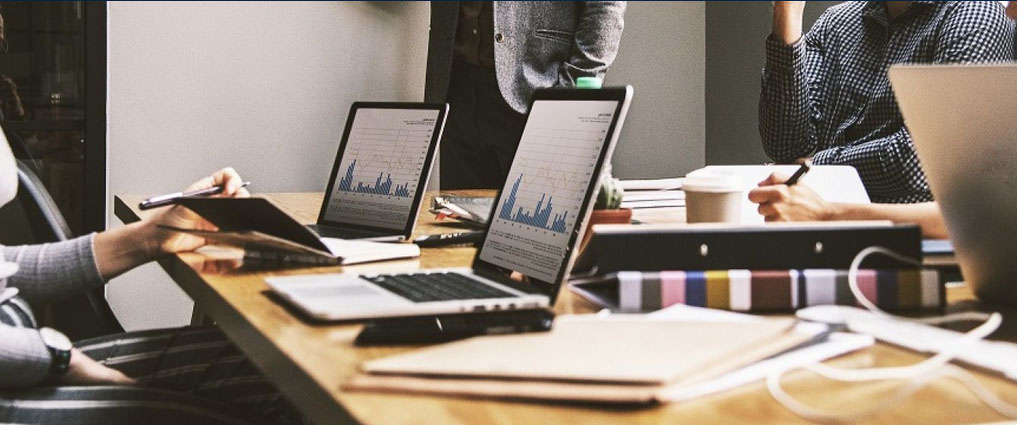 View of computers on a table during a meeting.