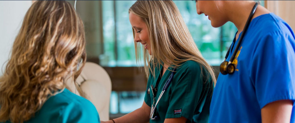 Nursing student standing next to two nurses.