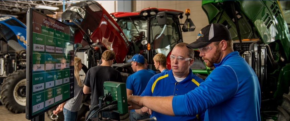 Instructor helping student with precision agriculture technology in lab.