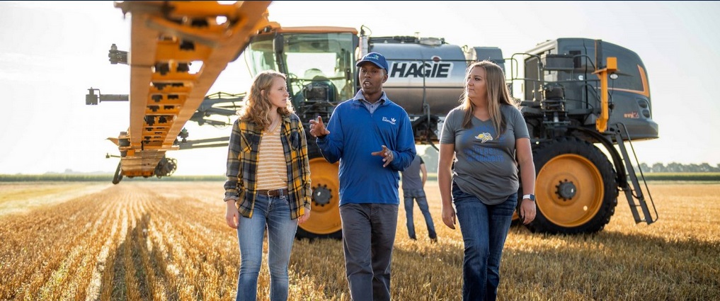 Students walking in a field listening to an instructor.