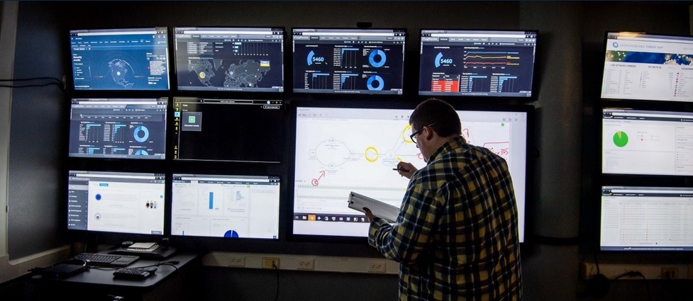 Student standing in front of monitors showing data.