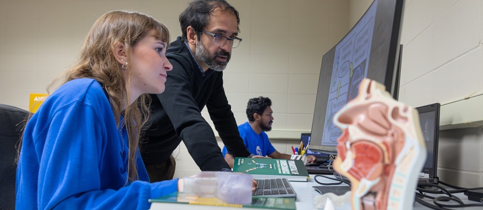 Student and professor looking at a computer screen.