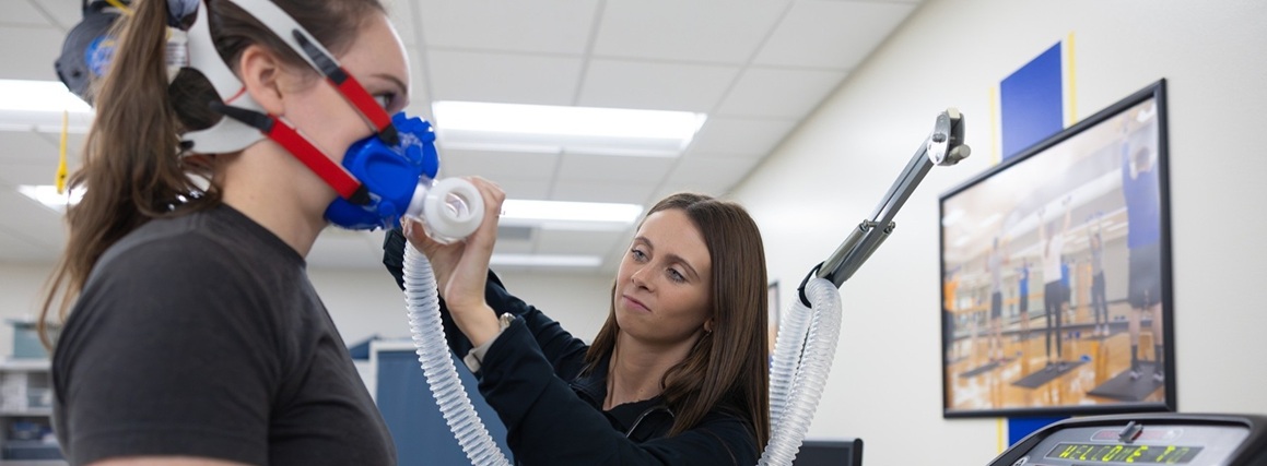 Lab technician adjusting VO2 testing equipment on participant