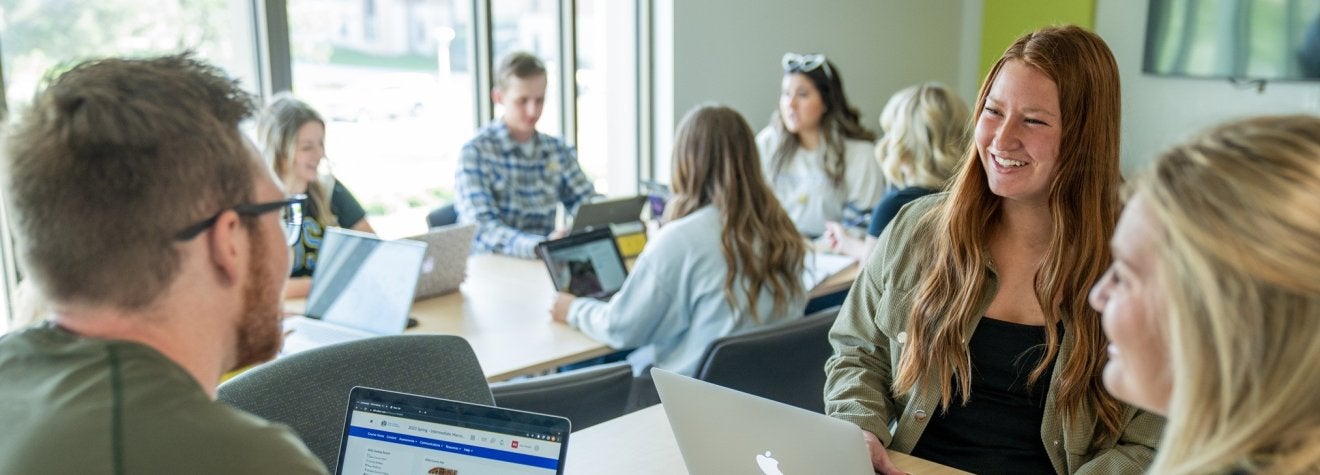 Two groups of students sitting at tables talking.