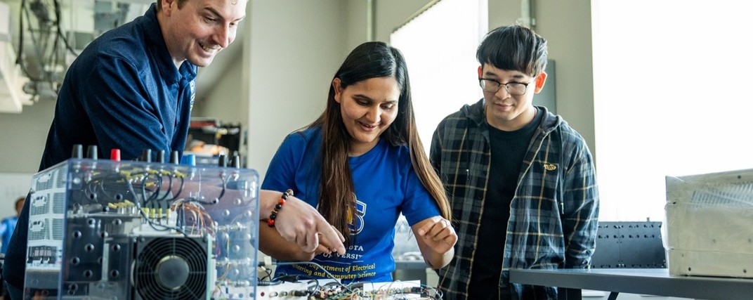An instructor working with students in an electrical engineering lab.