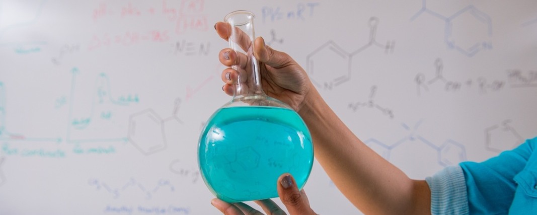 Glass beaker with light blue liquid in it.