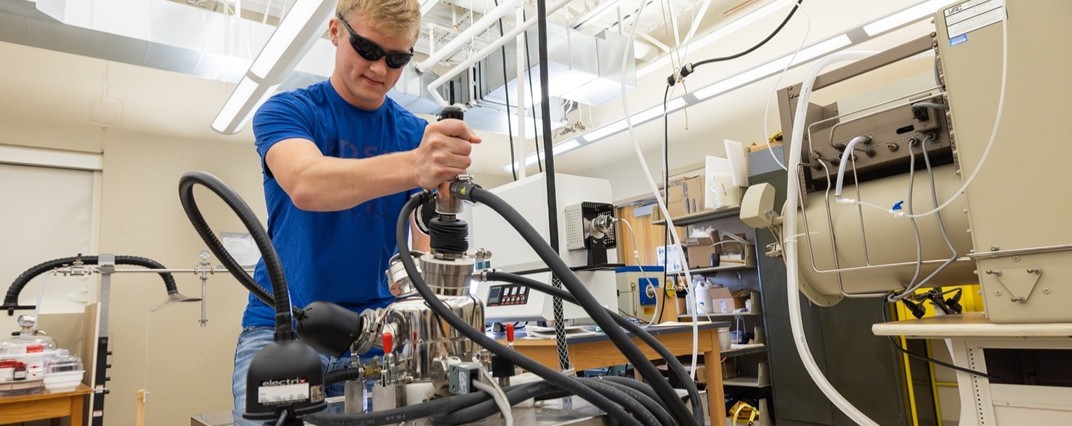 Student working in a physics lab and looking at a computer.