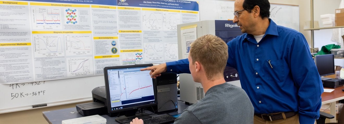 Professor and student looking at data on a computer screen.